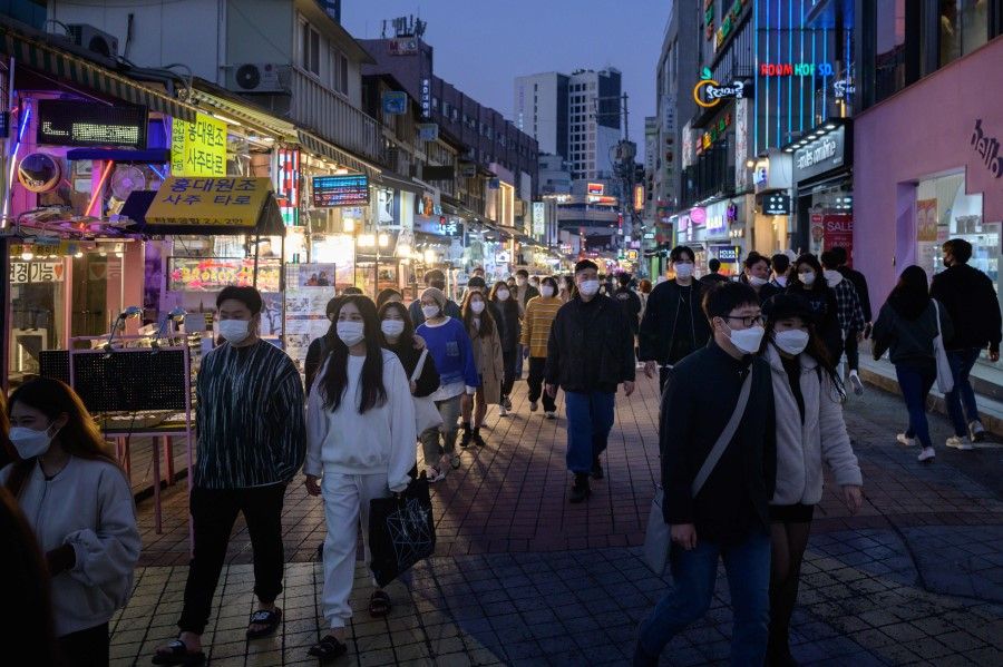 In a photo taken on 18 October 2020 people wearing face masks walk on a street in the Hongdae district of Seoul. (Ed Jones/AFP)
