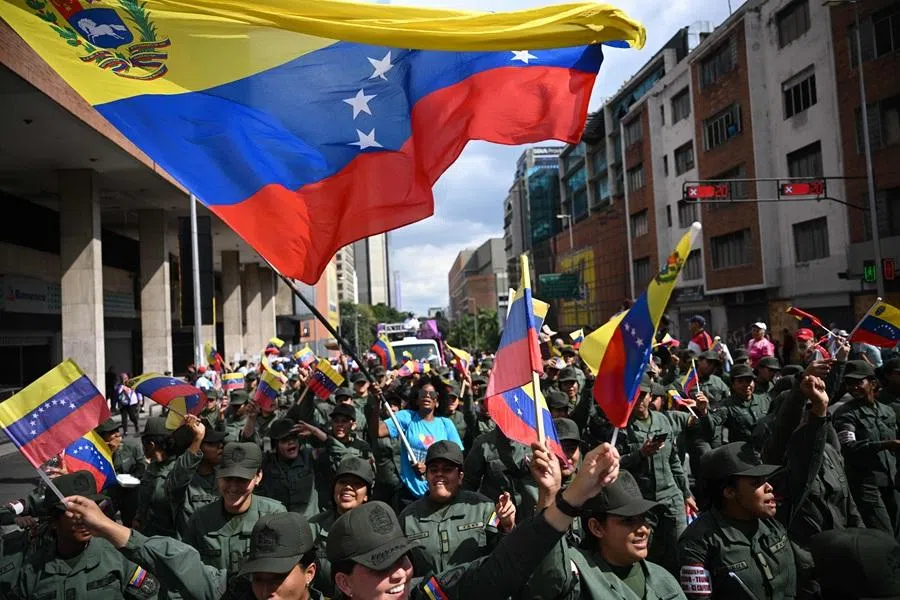 A woman waves a Venezuelan flag among members of the National Bolivarian Armed Forces during a rally in support of ousted Venezuela's President Nicolás Maduro and his wife Cilia Flores in Caracas on 6 January 2026. (Federico Parra/AFP)