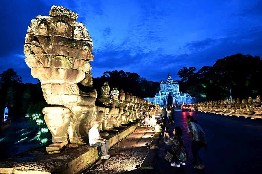 Visitors take pictures of the Angkor Thom south gate at the Angkor complex in Siem Reap province, Cambodia, 16 September 2024. (Tang Chihn Sothy/AFP)