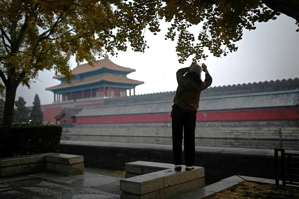 A woman takes a picture along the moat outside the Forbidden City in Beijing, China, on 21 November 2023. (Wang Zhao/AFP)