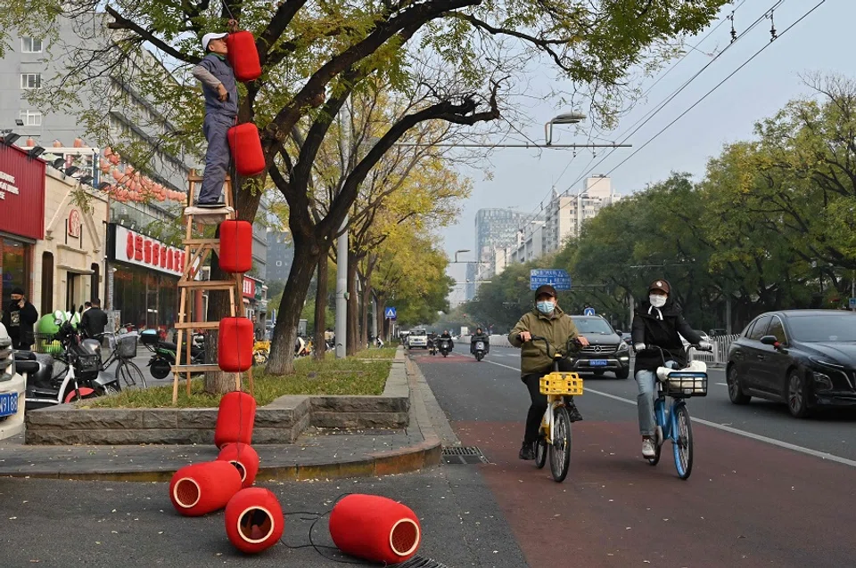 A man installs lanterns outside a newly opened restaurant in Beijing on 9 November 2024. (Adek Berry/AFP)
