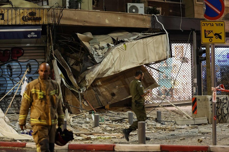 A rescuer walks in front of a damaged shop in Tel Aviv, Israel, after it was hit by a rocket fired by Palestinian militants from the Gaza Strip on 7 October 2023. (Jack Guez/AFP)