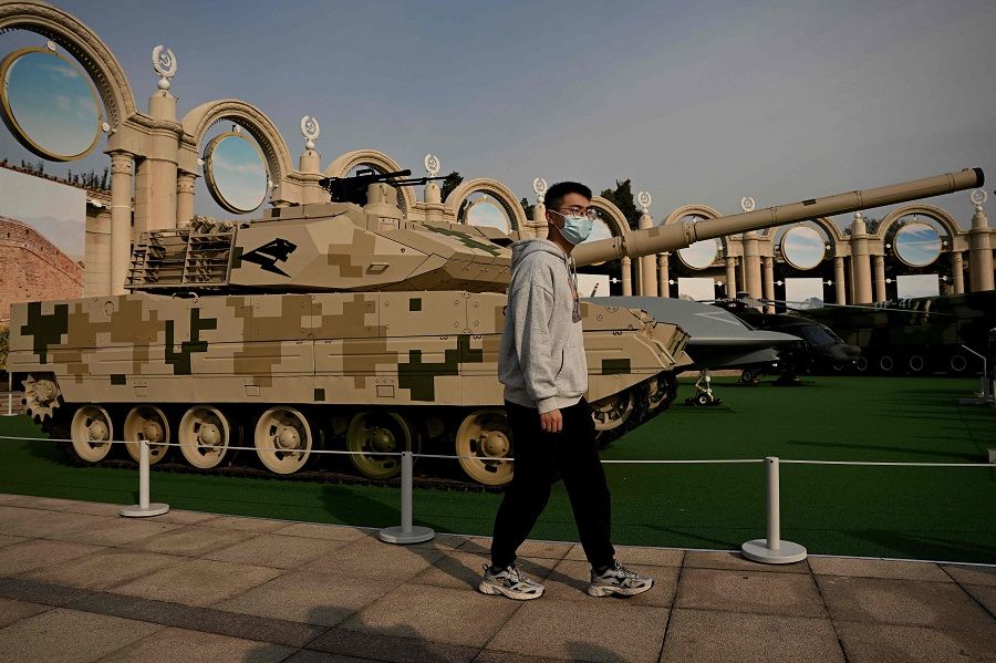A man walks past a Type 15 tank on display at the Beijing Exhibition Center, where an exhibition entitled "Forging Ahead in the New Era" showing the country's achievements during China's President Xi Jinping's past two terms is currently ongoing, ahead of the 20th Party Congress meeting in Beijing, China, on 12 October 2022. (Noel Celis/AFP)