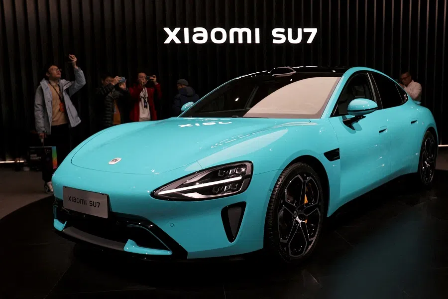 Visitors film around Xiaomi's first electric vehicle, the SU7, displayed at an event in Beijing, China, on 28 December 2023. (Florence Lo/Reuters)