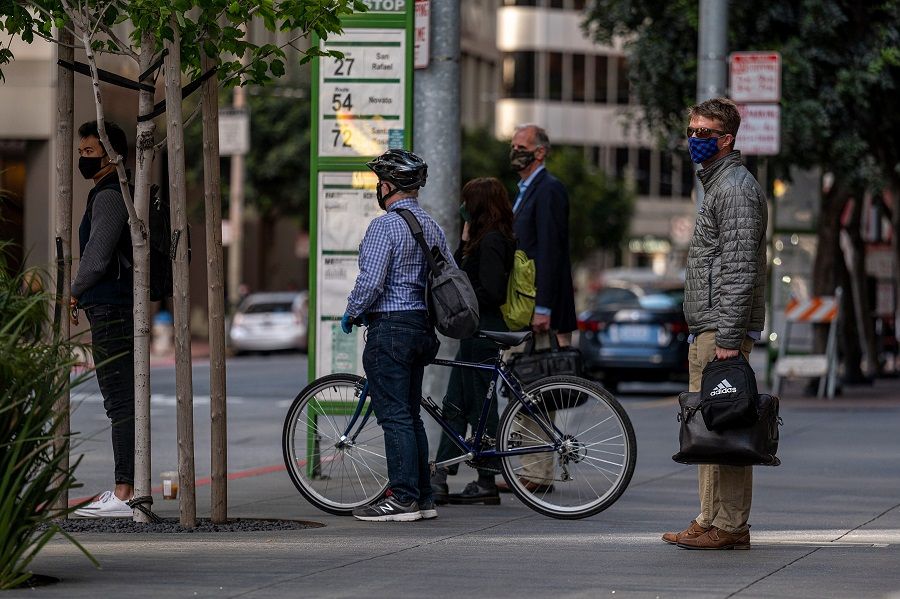 Commuters wearing protective masks wait for a bus in San Francisco, California on 9 June 2021. (David Paul Morris/Bloomberg)