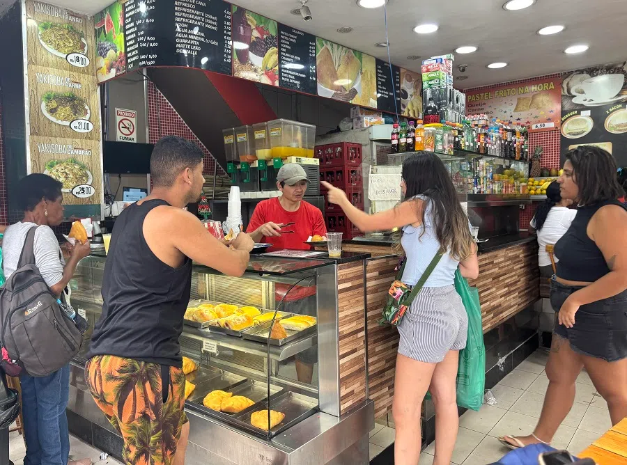 Zhu Jun (in red), an immigrant from Guangdong, runs a corner shop in Rio de Janeiro. (SPH Media)