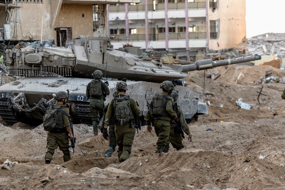 Israeli soldiers walk through rubble, amid the ongoing ground invasion against Hamas in the northern Gaza Strip, on 8 November 2023. (Ronen Zvulun/Reuters)