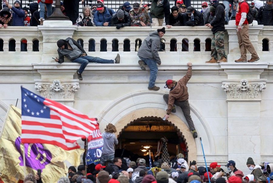 A mob of supporters of US President Donald Trump fight with members of law enforcement at a door they broke open as they storm the US Capitol Building in Washington, US, 6 January 2021. (Leah Millis/REUTERS)