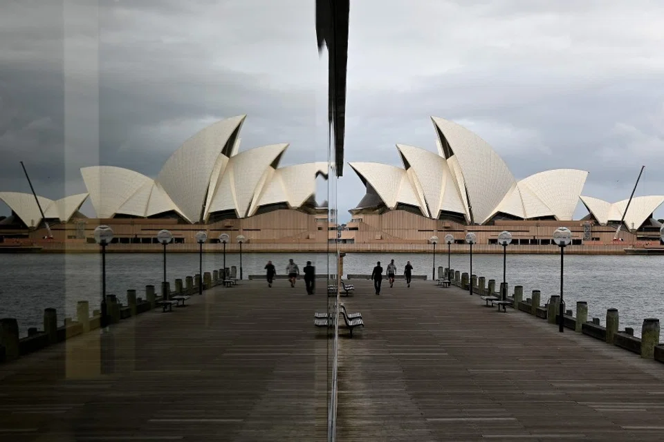 People walk before the Opera House, usually packed with tourists, in Sydney, on 18 May 2020. (Saeed Khan/AFP)