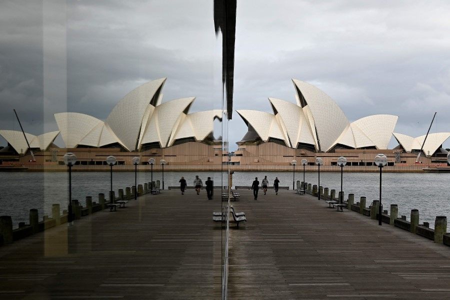 People walk before the Opera House, usually packed with tourists, in Sydney, on 18 May 2020. (Saeed Khan/AFP)