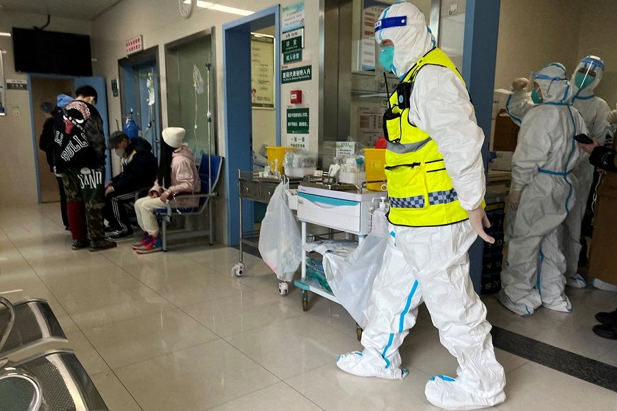 A security personnel in a protective suit keeps watch as medical workers attend to patients at the fever department of Tongji Hospital, a major facility for Covid patients, in Wuhan, Hubei province, China, on 1 January 2023. (Staff/File Photo/Reuters)