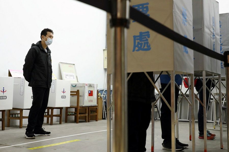 An electoral worker keeps watch as people cast their votes at a polling station during a four-question referendum in Taipei, Taiwan, 18 December 2021. (Annabelle Chih/Reuters)