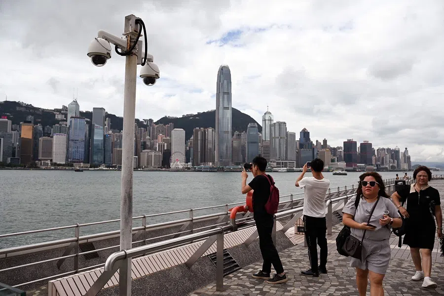 This photo taken on 13 September 2023 shows surveillance cameras (left) as people walk along the Kowloon side of Victoria Harbour in Hong Kong. (Peter Parks/AFP)