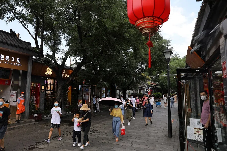 People walk at the Nanluoguxiang alley in Beijing, China, 20 August 2021. (Tingshu Wang/Reuters)