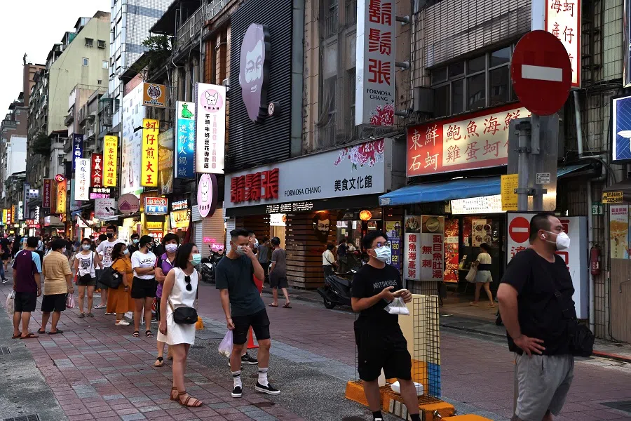 People wearing protective masks wait for their food at a newly opened night market in Taipei on 2 July 2021. (Ann Wang/Reuters)