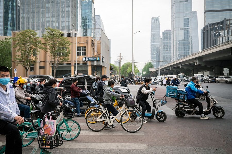 Cyclists and vehicles wait at a traffic signal light in Beijing, China on 21 April 2021. (Yan Cong/Bloomberg)
