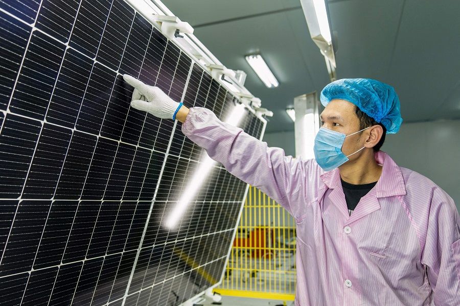 This file photo taken on 7 January 2022 shows a worker checking solar photovoltaic modules used for small solar panels at a factory in Hai'an, Jiangsu province, China. (AFP)