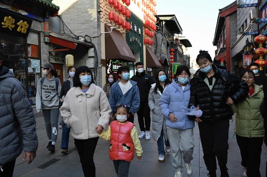 People wearing masks walk on a street in Beijing on 13 November 2021. (Jade Gao/AFP)