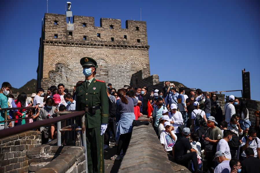 Paramilitary police officers keep watch as people climb the Great Wall of China in Beijing, China, 1 October 2021. (Thomas Peter/Reuters)