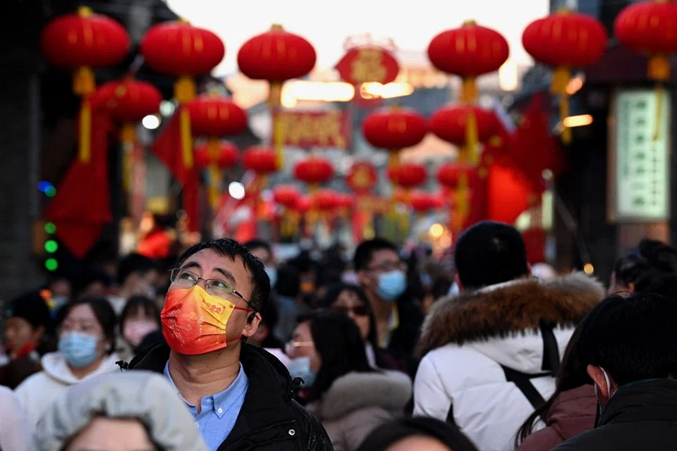 People walk through an alley decorated with traditional lanterns near Houhai lake in Beijing, China, on 2 February 2022. (Noel Celis/AFP)