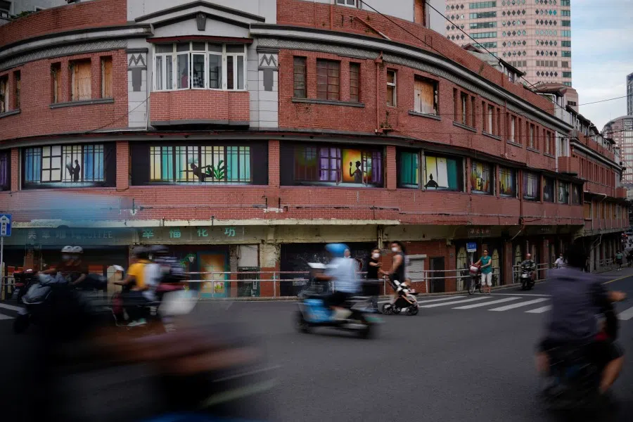 People cross the street in front of an empty building in Shanghai, China, 9 September 2022. (Aly Song/Reuters)