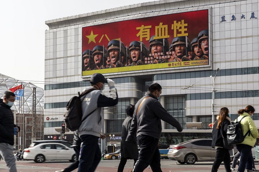 Pedestrians pass a screen showing a video promoting the People's Liberation Army (PLA) in Beijing, China, on 4 March 2022. (Qilai Shen/Bloomberg)