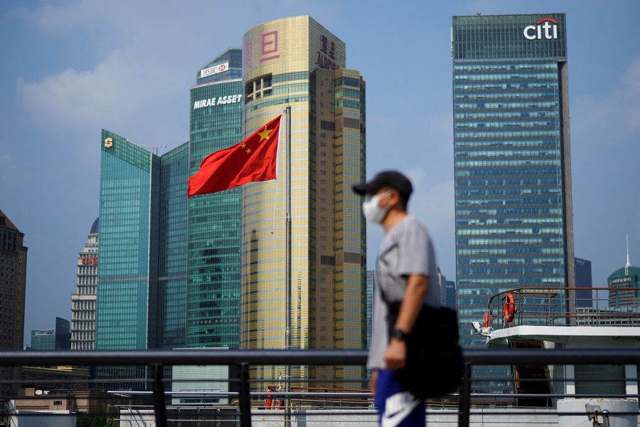 A man wearing a face mask following the Covid-19 outbreak walks past a Chinese flag in Shanghai, China, 2 August 2022. (Aly Song/Reuters)