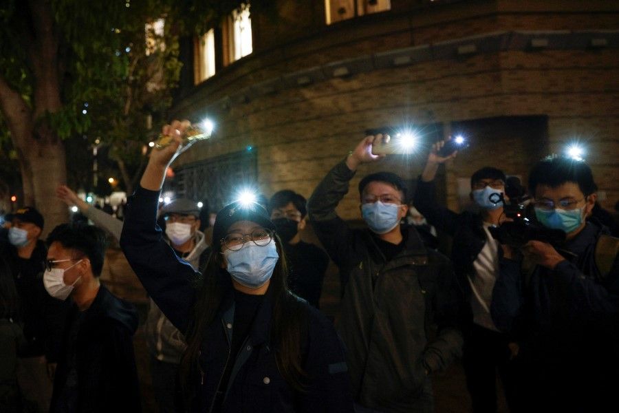 Supporters of pro-democracy activists hold they flashlights as a prison van carrying some of the 47 pro-democracy activists charged with national security law leaves West Kowloon Magistrates' Courts, in Hong Kong, 4 March 2021. (Tyrone Siu/Reuters)