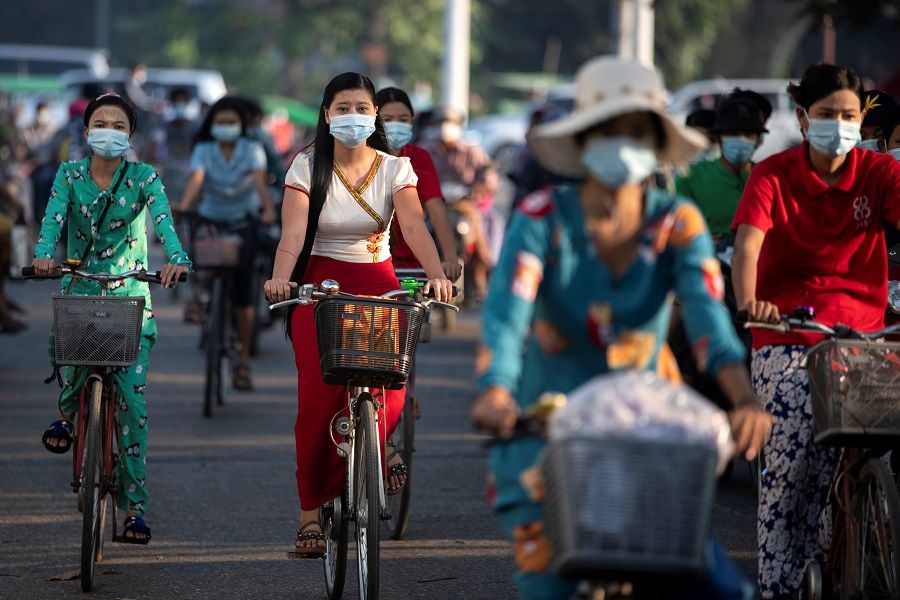 People wearing protective face masks ride bikes on a street in Yangon, Myanmar, 7 December 2020. (Shwe Paw Mya Tin/Reuters)