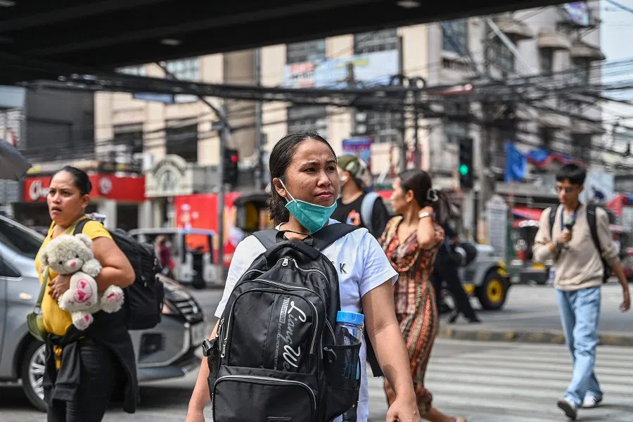 People cross a street in Manila, Philippines, on 21 August 2024. (Jam Sta Rosa/AFP)