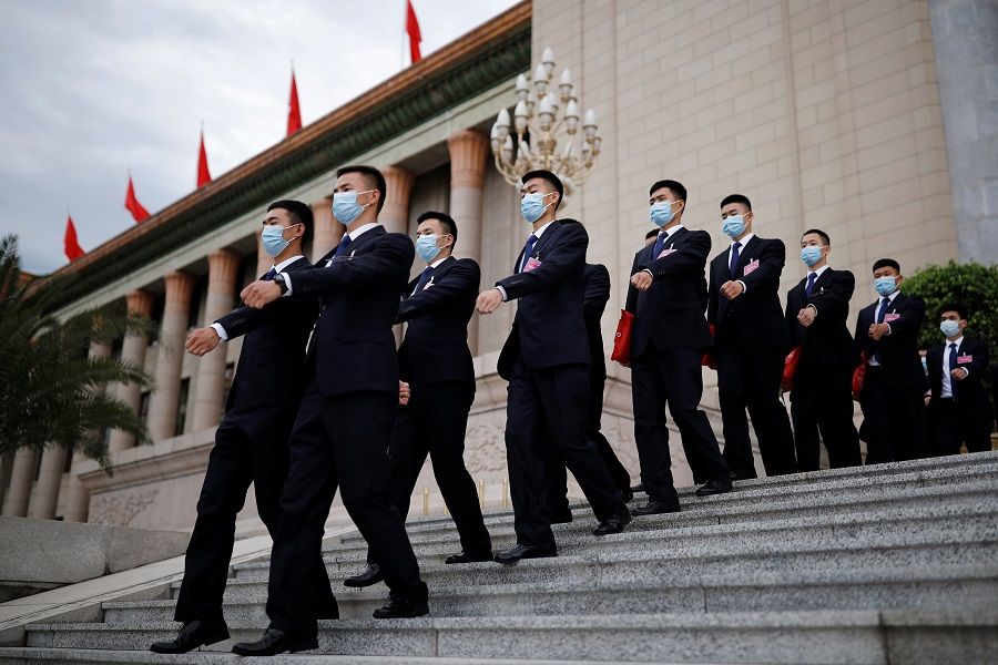 Security personnel wearing masks following the Covid-19 outbreak march outside the Great Hall of the People after the second plenary session of the National People's Congress in Beijing, China, on 25 May 2020. (Thomas Peter/Reuters)