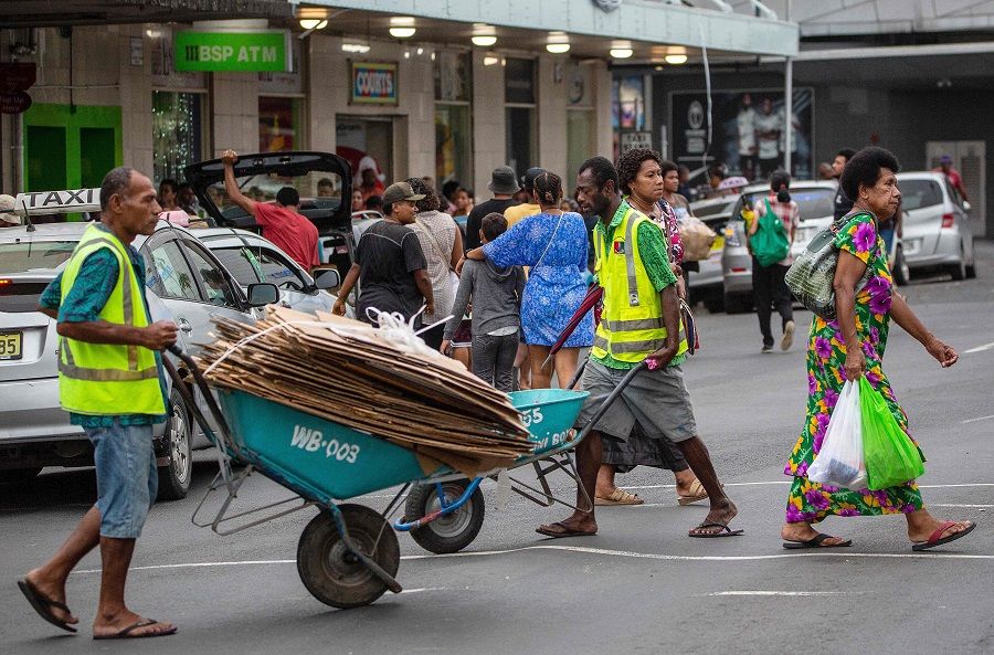 People walk across a street in Fiji's capital city Suva on 22 December 2022. (Leon Lord/AFP)
