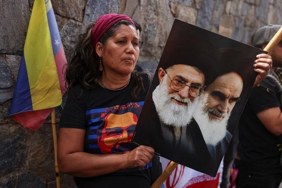 A woman wearing a t-shirt featuring a depiction of ousted President Nicolás Maduro holds a picture of Iran's late Supreme Leaders, Ayatollah Ali Khamenei, and Ayatollah Ruhollah Khomeini, as demonstrators participate in a rally in support of Iran, following the Israel and US strikes on Iran and the killing of the country's Supreme Leader, in Caracas, Venezuela, 3 March 2026.