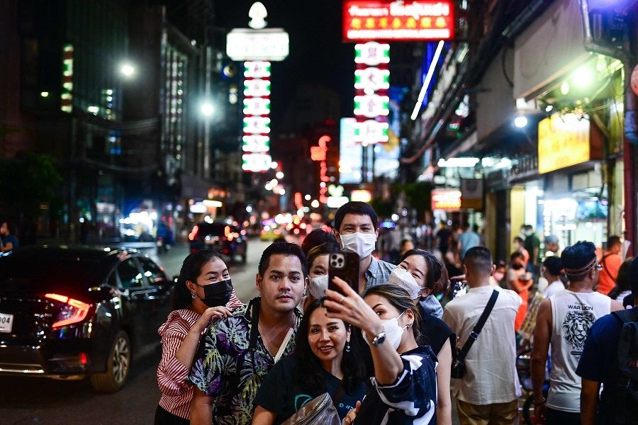 Tourists pose for a selfie along the popular Yaowarat Road in the Chinatown area of Bangkok, Thailand, on 5 September 2022. (Manan Vatsyayana/AFP)