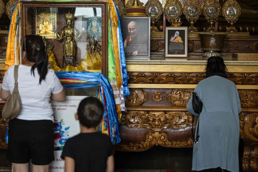 Buddhist devotees pray next to a portrait of Tibetan spiritual leader the Dalai Lama (centre) at the Gandantegchinlen Monastery in Ulaanbaatar, capital of Mongolia, on 4 July 2025. (Byambasuren Byamba-Ochir/AFP)