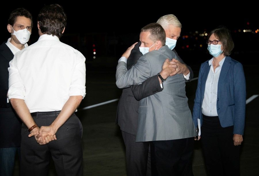 Michael Kovrig and Michael Spavor, accompanied by Canada's ambassador to China, Domenic Barton, are greeted on arrival by Prime Minister Justin Trudeau after being released from detention in China, in Calgary, Alberta, Canada, 25 September 2021. (DND-MDN Canada/Handout via Reuters)