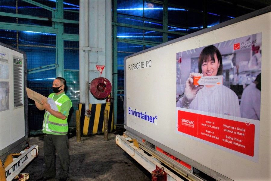 An officer checks a container with COVID-19 vaccines from China's Sinovac Biotech Ltd., as they arrive at Soekarno-Hatta International Airport in the first shipment to Indonesia, in Tangerang, near Jakarta, 6 December 2020. (Dhemas Reviyanto/Antara Foto via Reuters)