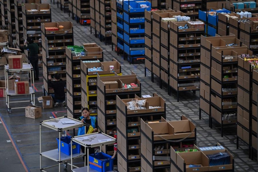 In this picture taken on 6 November 2020, employees put products in shelves which are then moved by robots in the warehouse of Cainiao Smart Logistics Network, the logistics affiliate of e-commerce giant Alibaba, in Wuxi, China's eastern Jiangsu province. (Hector Retamal/AFP)