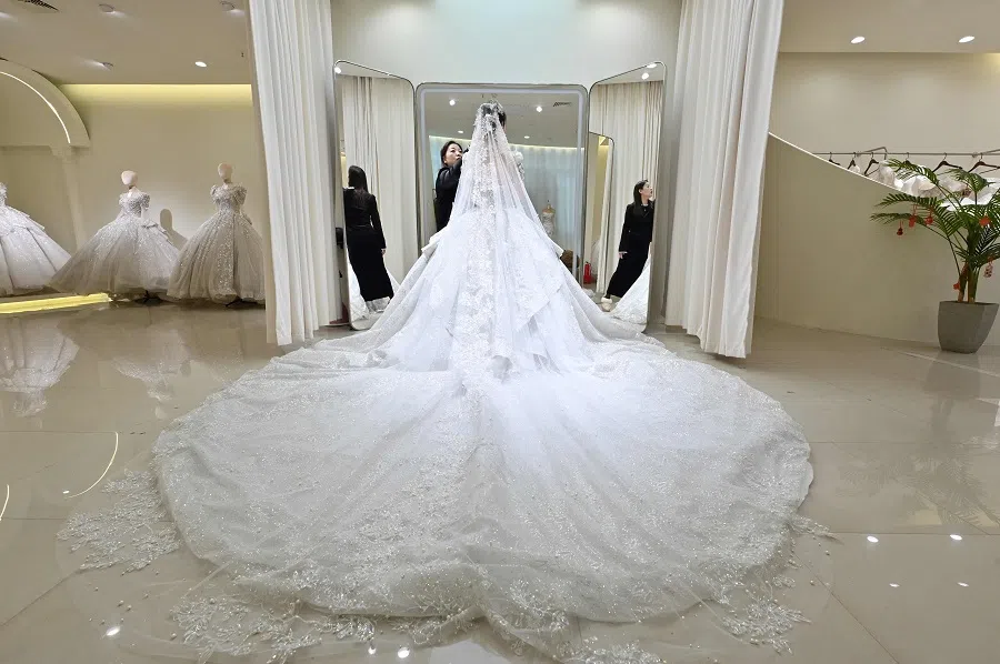 A woman fits her wedding dress at a bridal shop in Luliang, northern China’s Shanxi province on 11 February 2025. (Adek Berry/AFP)