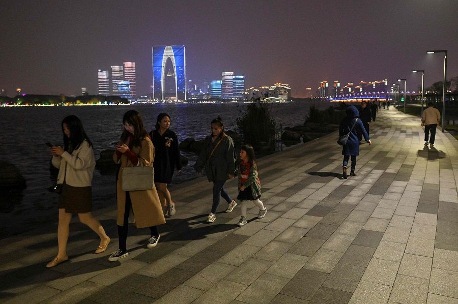 People walk on a promenade next to the Jinji Lake in Suzhou, Jiangsu province, China, on 12 April 2021. (Hector Retamal/AFP)