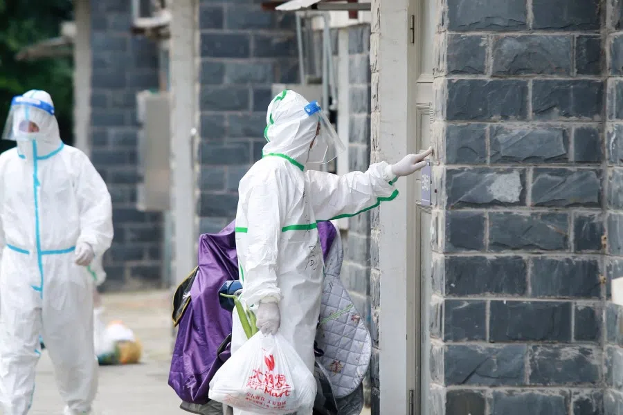 Volunteers and staff members wearing personal protective equipment (PPE) against the spread of Covid-19 coronavirus carry foods and daily necessities as they prepare to deliver for residents at a restricted residential area due to the virus in Yangzhou, in China's eastern Jiangsu province on 6 August 2021. (STR/AFP)