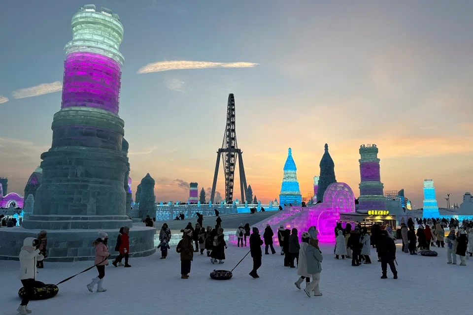 Visitors walk past ice sculptures at the Harbin Ice and Snow Festival in Harbin, Heilongjiang province, China, 24 December 2023. (Liz Lee/Reuters)