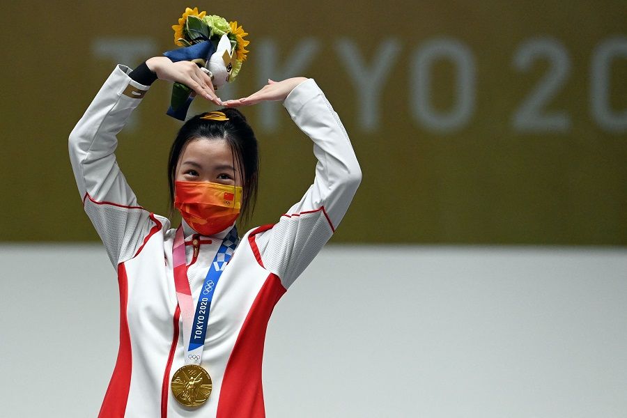 China's Yang Qian celebrates on the podium after winning the women's 10m air rifle final during the Tokyo 2020 Olympic Games at the Asaka Shooting Range in the Nerima district of Tokyo, Japan, on 24 July 2021. (Tauseef Mustafa/AFP)