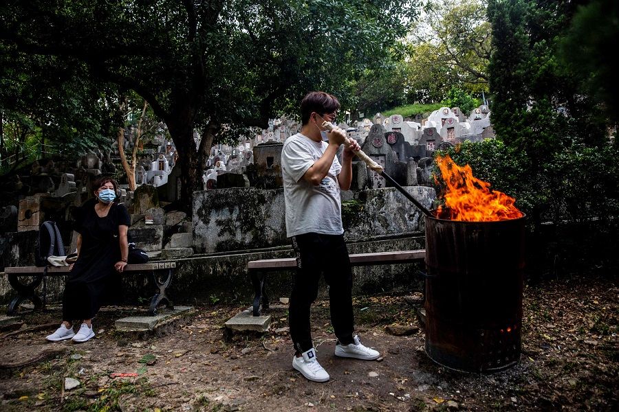 A man burns offerings in a barrel at a cemetery in Diamond Hill in Hong Kong on 14 October 2021, during the Chung Yeung Festival, also known as the Double Ninth Festival, where people honour their ancestors. (Isaac Lawrence/AFP)