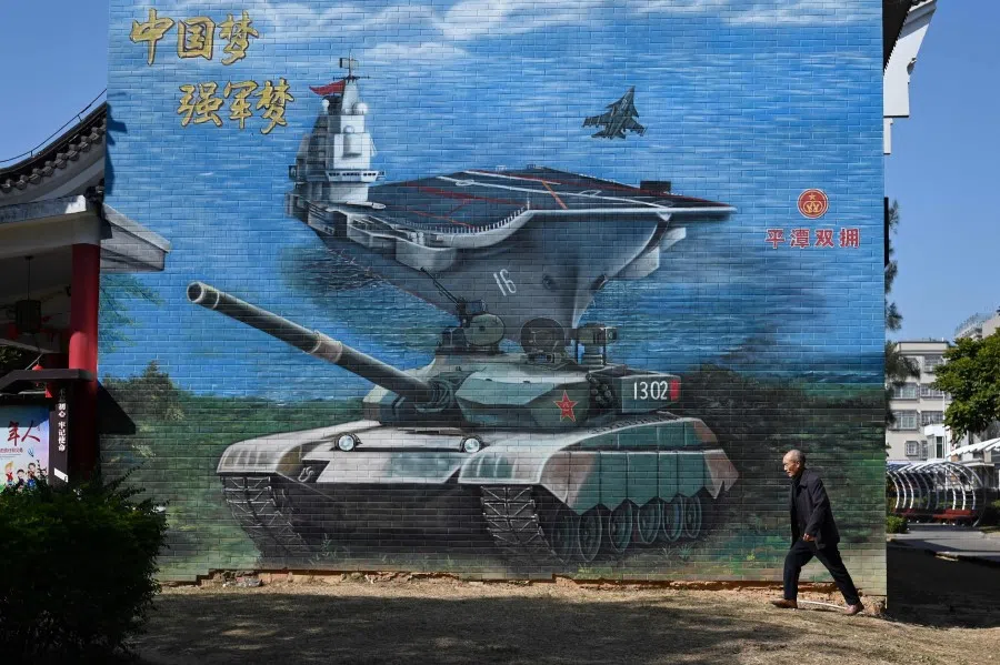 A man walks past a military-themed mural at a public park on Pingtan Island, the closest point in China to Taiwan's main island, in China's southeast Fujian province on 14 January 2024, the morning after Taiwan's presidential election. The slogan at left reads: "China dream; strong-army dream." (Greg Baker/AFP)