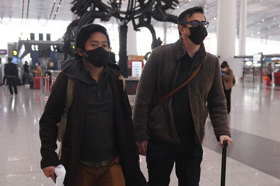 Wall Street Journal reporters Josh Chin (right) and Philip Wen walk through Beijing Capital Airport before their departure on 24 February 2020. (Greg Baker/AFP)