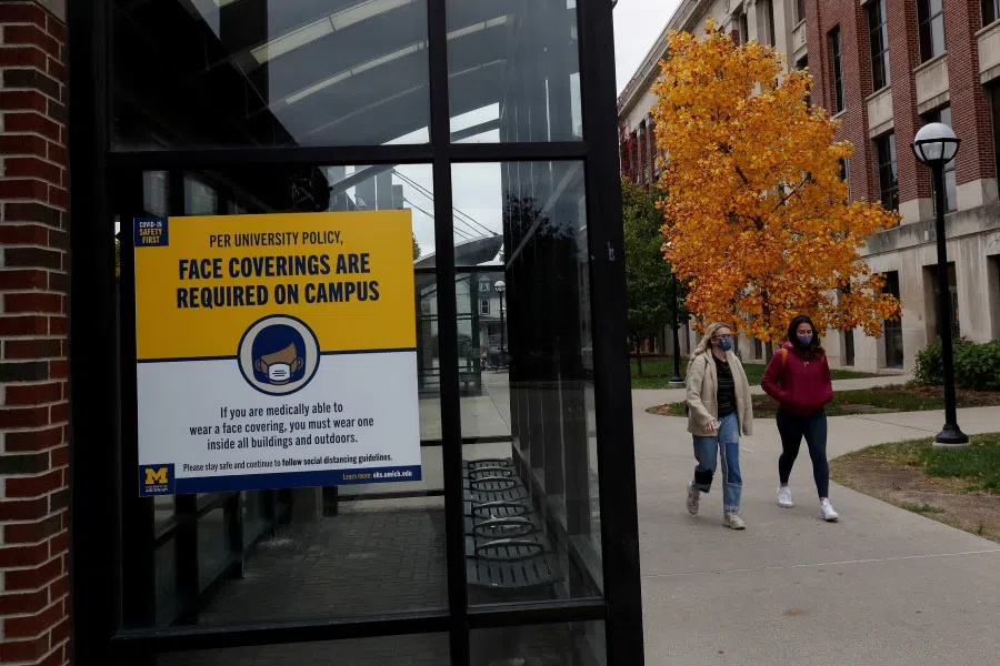 Women with protective face masks walk on the University of Michigan campus, where state health officials in Michigan issued a stay-in-place order for undergraduate students, in Ann Arbor, Michigan, US, 26 October 2020. (Shannon Stapleton/REUTERS)