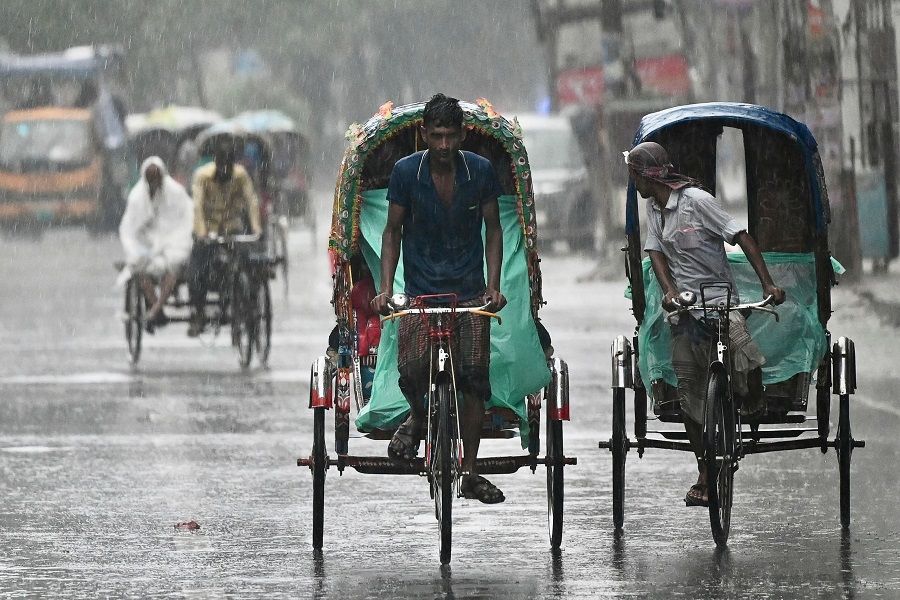 Rickshaw pullers make their way along a street during a rainfall in Dhaka, Bangladesh, on 9 June 2023. (Munir Uz Zaman/AFP)