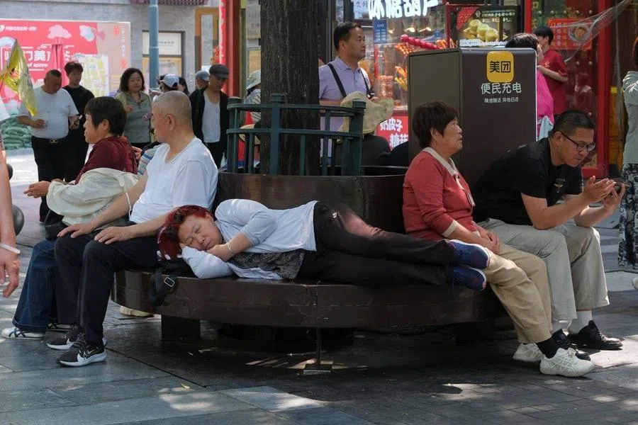 People rest on a bench along Qianmen pedestrian street, in Beijing, China, on 13 May 2026.