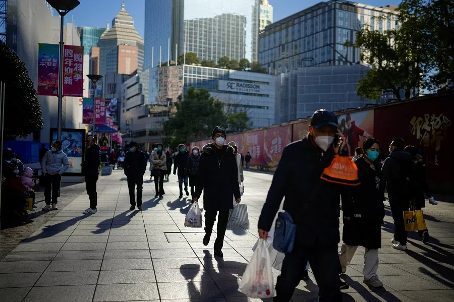 People wearing protective masks walk in a shopping district in Shanghai, China, 3 January 2023. (Aly Song/Reuters)